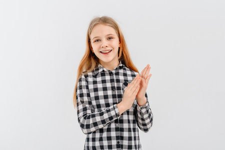 Smiling teen girl in casual plaid shirt, clap hands, applauding you and praising, looks happy, stands over white backgroundの写真素材