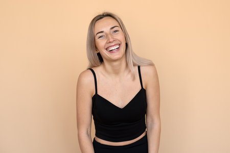 A Portrait of a happy young woman with freckles posing against beige background. Beautiful female model smilingの写真素材