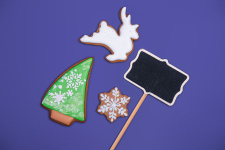 White deer shaped, christmas tree and snowflake shaped gingerbread cookie and space for text on purple background, top view. close-up. Homemade Christmas cookies. Happy new year and merry christmas conceptの写真素材