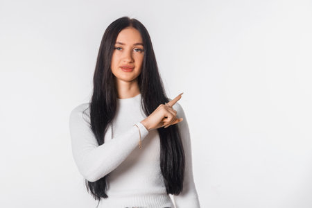 Confident young woman pointing finger aside and up, showing advertisement. Portrait of serious student, secretary, girl, female over white studio background. copy spaceの写真素材