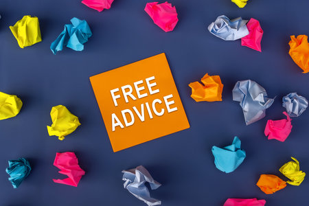 Free Advice - inscription of a orange paper note next to an many colorful crumpled paper balls around it on purple background. business conceptの写真素材