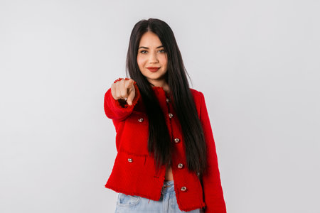 Its you. Lovely girl with long hair, points finger at camera and looks confident, standing over white background. Young leader woman wearing stylish red blazer points index finger on youの写真素材