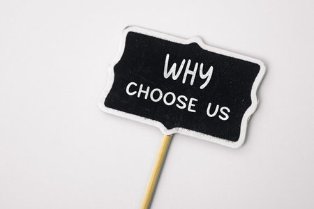 Why choose us - text on a small chalkboard on a neutral background. Top view. Concept meaning list of advantages and disadvantages to select product or serviceの写真素材