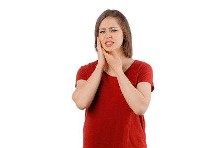 Young brunette woman touching mouth with hand with painful expression because of toothache or dental illness on teeth, posing over white background. Tooth Pain And Dentistryの写真素材