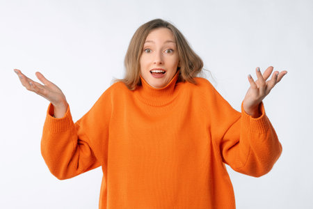 Confused young woman spread hands sideways and staring frustrated, shrugging shoulders, standing puzzled against neutral backgroundの写真素材