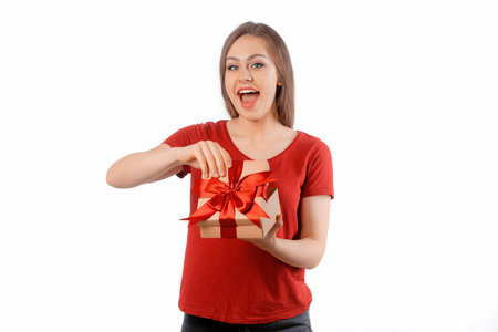 Portrait of a happy smiling girl opening a gift box and posing over white background. International Women's Day, New Year, Christmas, Birthday and Valentine's Day concept celebrationの写真素材