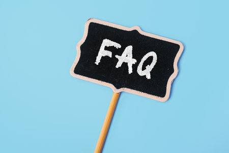 FAQ - Frequently Asked Questions - text on a small chalkboard on a blue background. top view. Instructions and rules on Internet sitesの写真素材