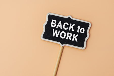 Back to work - text on a small chalkboard on a beige background. top view. The concept education, training, after vacation, maternity leave, breakの写真素材