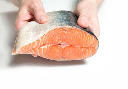 Closeup of a big piece of salmon fish in male hands. Fresh fish before cooking.の写真素材