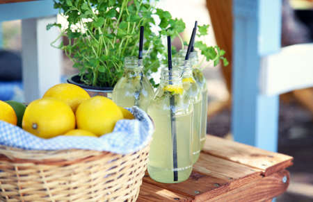 Fresh lemonade and a basket with lemons on a wooden table on a summer hot day.の写真素材