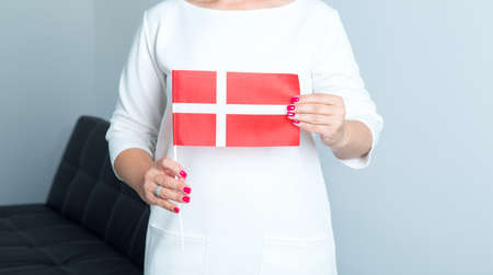 Close up of a woman holding a flag of Denmark in front of herself.の写真素材