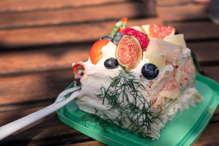 Sunlit table features layered cream cake with fresh fruitの写真素材