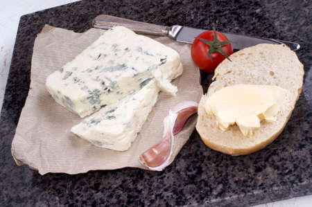 french blue cheese on marble with knife and bread rollの写真素材
