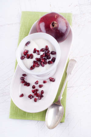 fresh yogurt with pomegrante seed on a small plateの写真素材