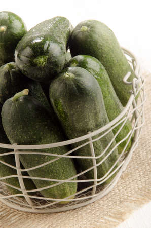 freshly picked gherkin in a basket on juteの写真素材