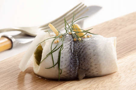 pickled herring with gherkin and onlion on a wooden boardの写真素材