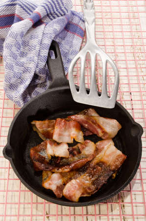 grilled bacon in cast iron pan on pink cooling rackの写真素材