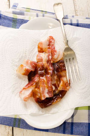 fried bacon on a plate to take excessive fat with kitchen paperの写真素材