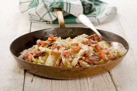 fried white cabbage with crushed peppercorn and bacon in a brass panの写真素材