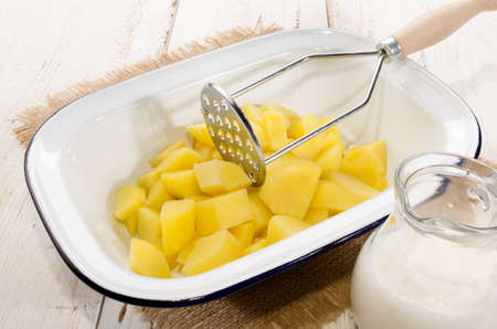 potato cubes in a enamel bowl and milk to make mashed potatoesの写真素材
