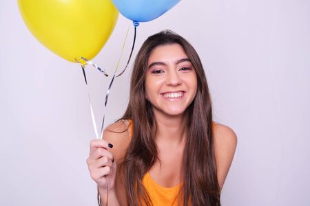 Happy young woman holding balloons. Caucasian beautiful woman isolated over grey background.の写真素材