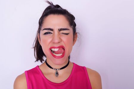 Closeup portrait of fashionable young woman doing fun expression. Urban stylish woman studio portrait over grey backgroung.の写真素材