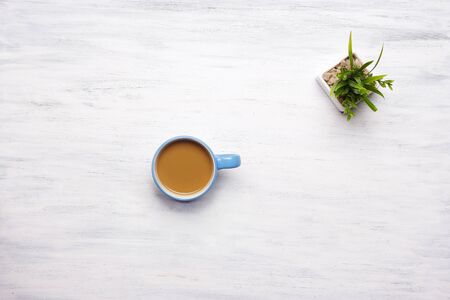 Top view of cup of coffee on a white wooden table. Break from work, lifestyle concept.