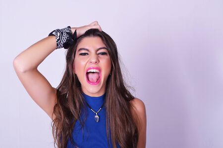 Portrait of fashionable young woman wearing stylish urban clothes. Caucasian woman doing shouting expression to the camera. Fashion studio portrait over grey backgroung.の写真素材