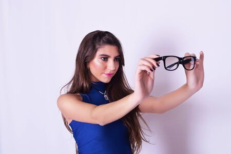 Portrait of fashionable young woman wearing stylish urban clothes, holding hipster glasses. Fashion...