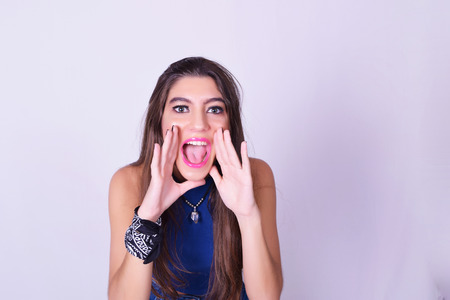 Portrait of fashionable young woman wearing stylish urban clothes, shouting to the camera. Fashion studio portrait over grey backgroung.の写真素材