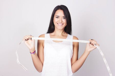 Young caucasian woman holding a measure tape. Fitness and diet concept. Healthy lifestyle.の写真素材