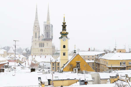 A view of the cathedral of Zagreb, Croatia, and picturesque roofs covered in snow.の写真素材