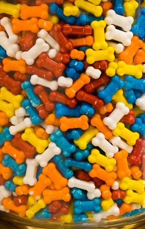 Colorful, bone-shaped candy bits in glass jar.の写真素材
