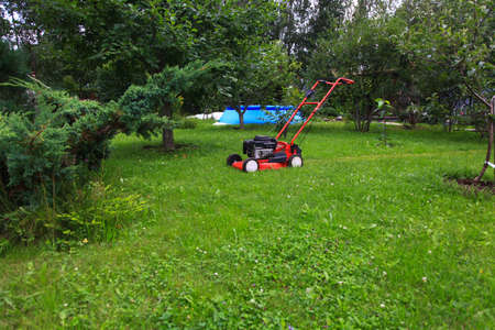 Blurred background of the home garden and lawn mower on mown grass.
