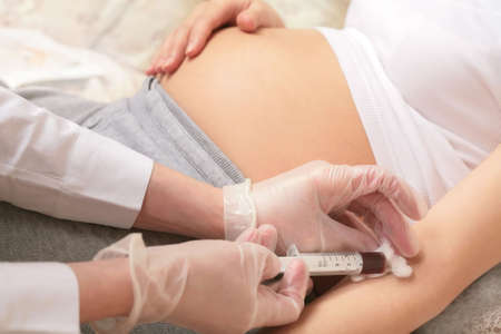 pregnancy, taking of a blood for analysis, hands of the doctor with syringeの写真素材