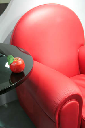 abstraction, fragment of the bright red leather easy chair with apple on edge of the tableの写真素材