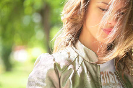 portrait of the beautiful smiling girl with brown hair shining under sunlight on windの写真素材