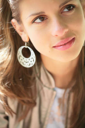 close-up portrait of the beautiful young brunette in silver earringの写真素材