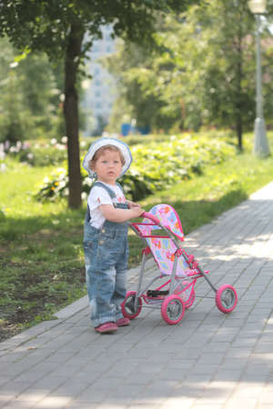 little girl walks in park with doll in sidercar and copy-spaceの写真素材