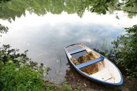 landscape with boat ashore calm lakeの写真素材