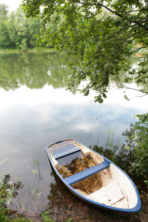 landscape with white-blue old boat ashore calm lakeの写真素材