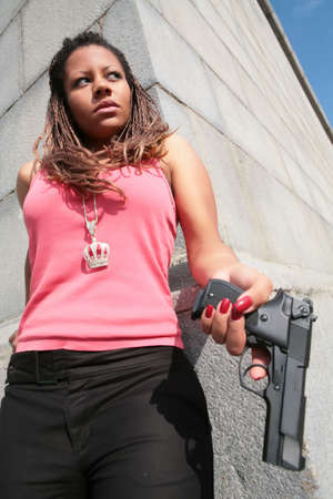 serious gangster woman in tanktop with big black gunの写真素材