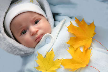 First autumn in life of my small son. Baby and autumn yellow maple leafの写真素材