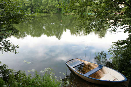 summer evening landscape with old boat on the coast on the calm lakeの写真素材