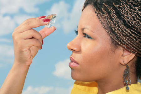 an african girl keeps in finger big diamond and looks through itの写真素材