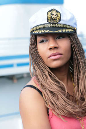 girl in red tanktop and captain cap on background of the motor shipの写真素材