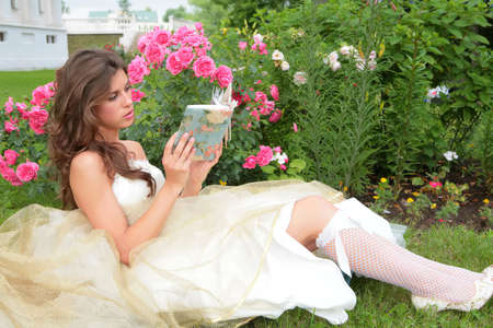 the young girl with book in hand under rosebushesの写真素材