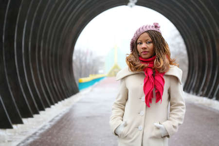 beautiful african girl in lilac beret, in light coat and bright red scarfの写真素材