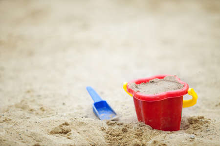 baby red bucket with sand and blue scoop. Small depth of sharpness. Copy-spaceの写真素材