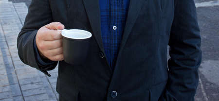 street coffee in a plastic cup in a man's hand against his jacketの写真素材